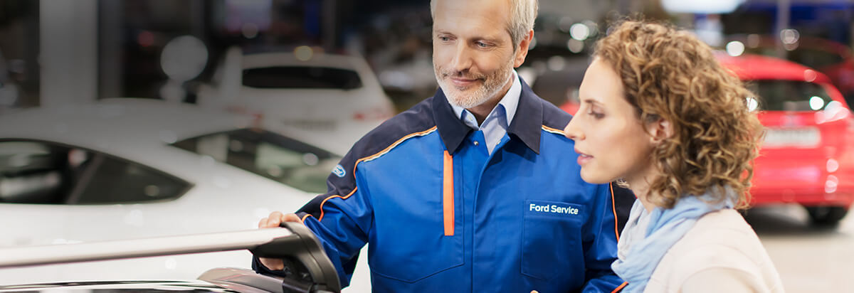 Ein Ford-Service-Mitarbeiter spricht mit einer Kundin über ein Fahrzeug in einer Autoshow.