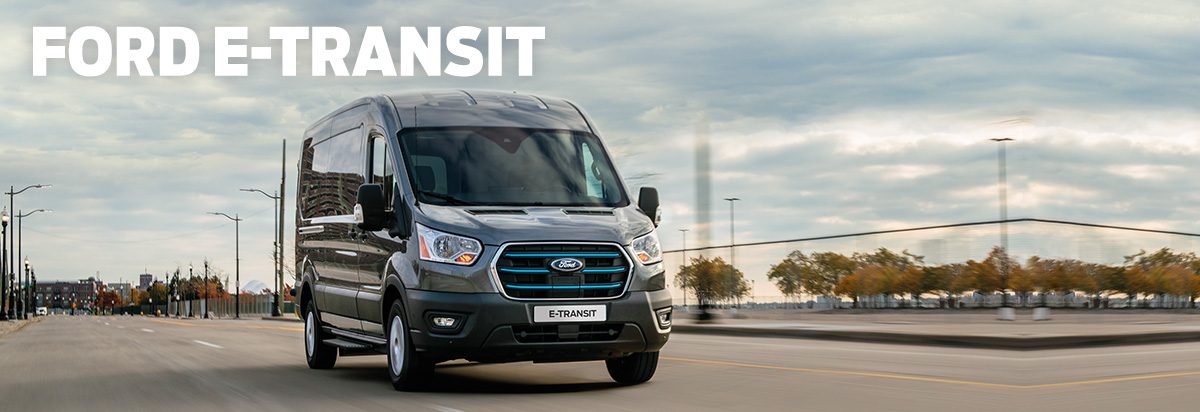 Ein Ford E-Transit fährt auf einer modernen Straße unter bewölktem Himmel, geeignet für Transport und Lieferung.