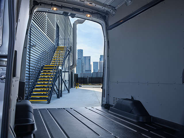 Blick in den offenen Innenraum eines Lieferwagens auf eine helle Stadtlandschaft mit Stufen und Gebäuden im Hintergrund.