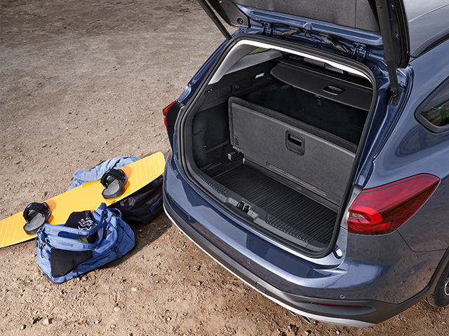 Kofferraum eines blauen Autos mit Snowboard und Taschen auf dem Boden. Ideal für Outdoor-Aktivitäten.