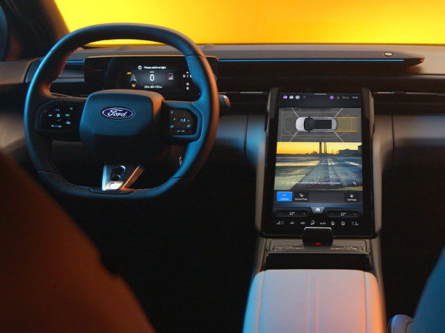 Innenansicht eines modernen Ford-Autos mit einem großen Touchscreen und einem Sportlenkrad.