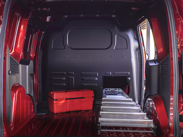 Ein Mann im Anzug trägt eine große Sporttasche zu einem Ford SUV vor einem modernen Gebäude.