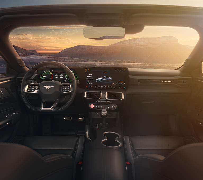 Innenansicht eines modernen Autos mit Blick auf eine bergige Landschaft bei Sonnenuntergang, digitale Anzeigen sichtbar.