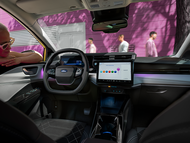 Blick ins Innere eines Ford-Autos mit digitalem Armaturenbrett und einer Person, die entspannt sitzt.
