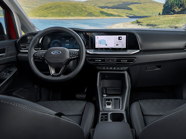 Innenansicht eines modernen Autos mit einem Ford-Lenkrad und einem digitalen Touchscreen-Display, Blick auf eine Landschaft.