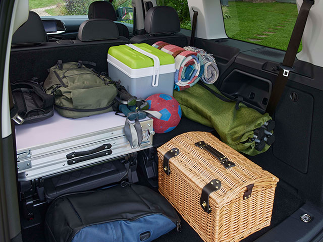 Kofferraum mit Gepäck, Kühlbox, Decken, Innenansicht eines SUVs, bereit für einen Ausflug.