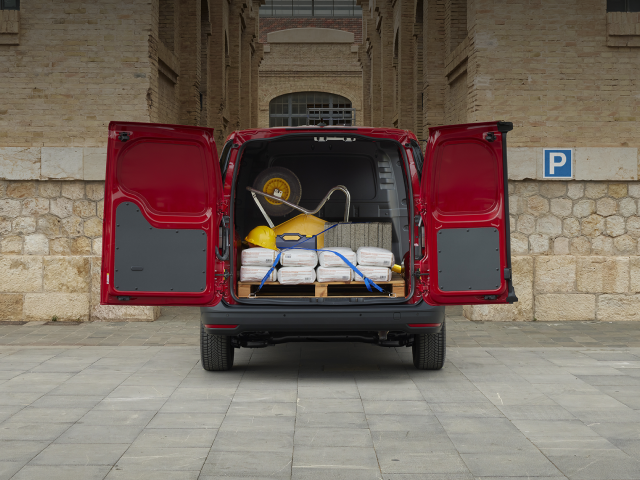 Roter Lieferwagen mit offenen Türen, beladen mit Baumaterialien und Werkzeug auf einer Palette.